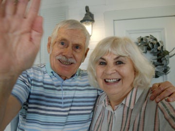 Pareja mayor saluda a la pantalla en una videoconferencia
