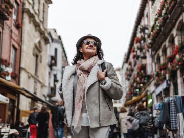 Se&ntilde;ora abrigada sonriendo mientras pasea por la calle