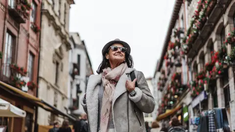 Los abrigos que arrasan este otoño entre las mujeres mayores de 50 Señora abrigada sonriendo mientras pasea por la calle