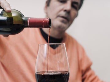 Hombre llenando una copa de vino