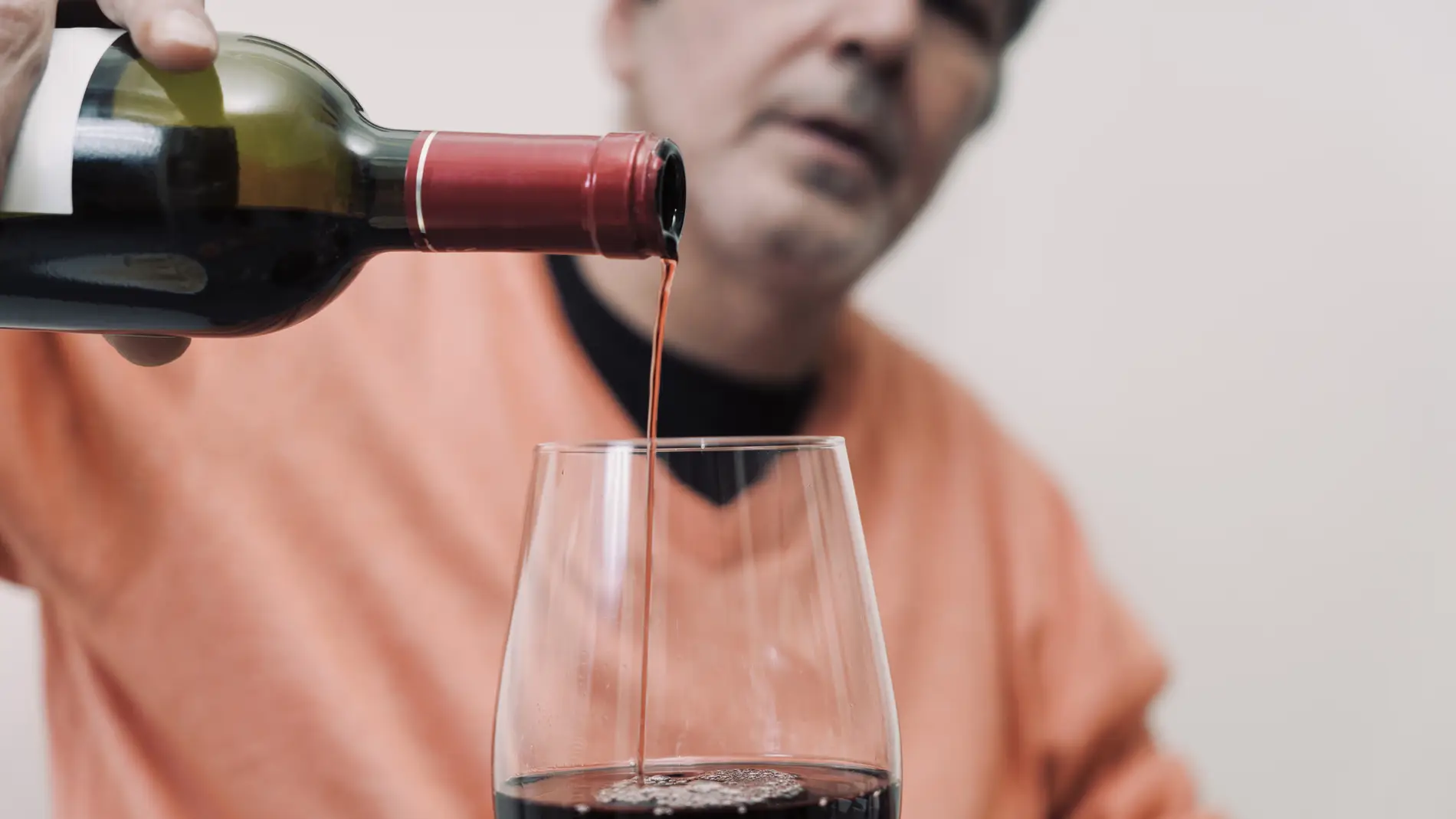 Hombre llenando una copa de vino
