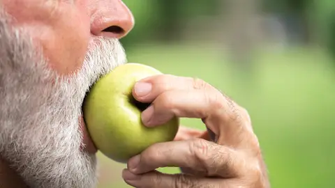 Hombre mayor comiendo una manzana Hombre mayor comiendo una manzana