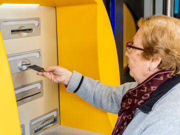 Una mujer mayor sacando dinero de un cajero automático
