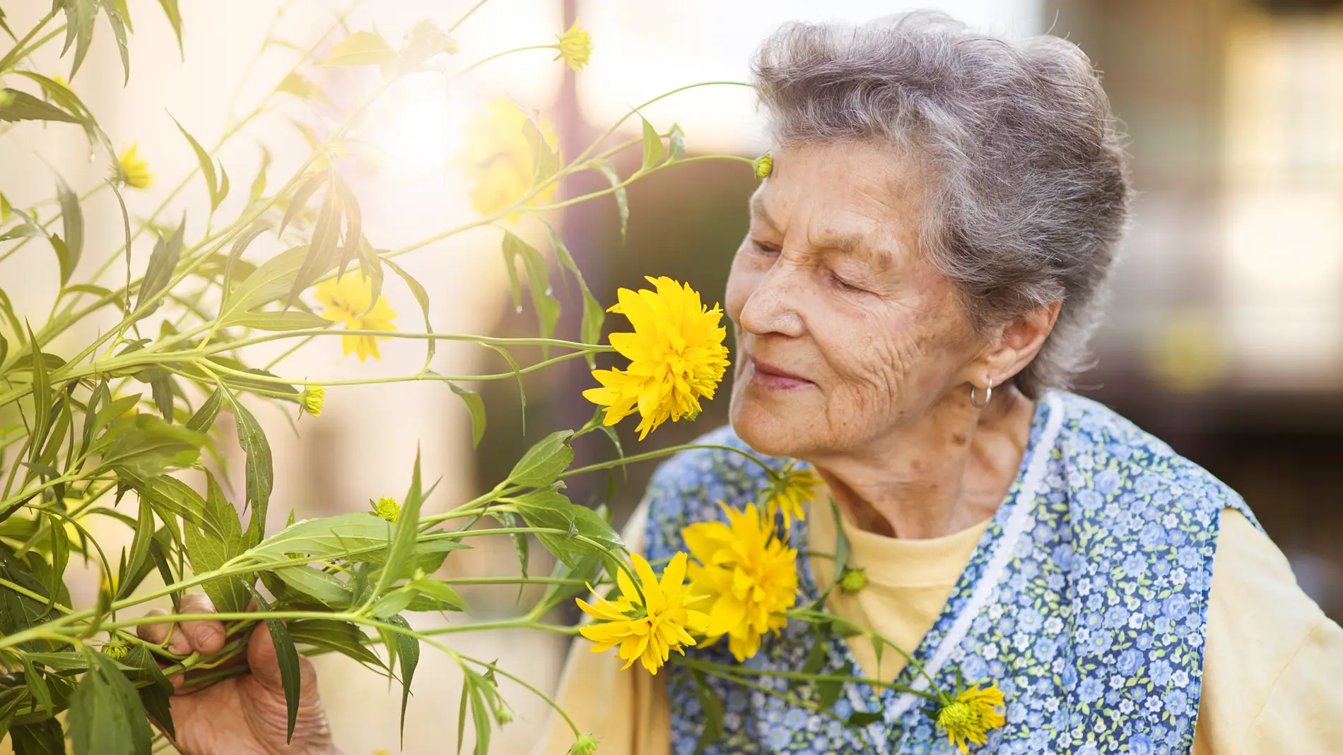 Una mujer mayor oliendo una flor
