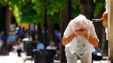 Una mujer refrescándose en una fuente Una mujer refrescándose en una fuente