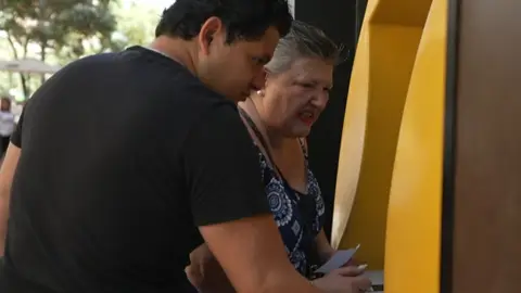 Una mujer sacando dinero del banco Una mujer sacando dinero del banco