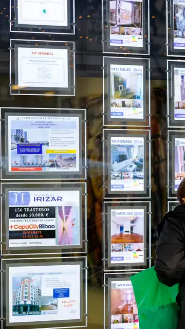 Una mujer observa en una inmobiliaria Una mujer observa en una inmobiliaria