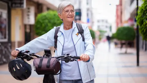 Mujer mayor en bicicleta por la ciudad Mujer mayor en bicicleta por la ciudad