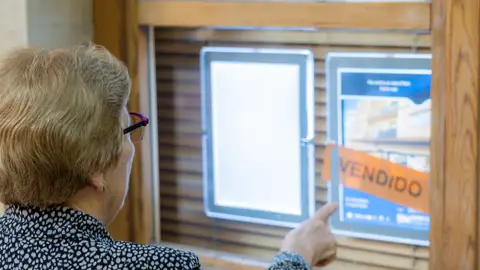Mujer mayor ante un portal inmobiliario Mujer mayor ante un portal inmobiliario