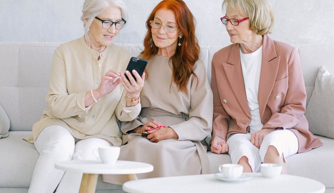 Mujeres charlando y consultando el m&oacute;vil 