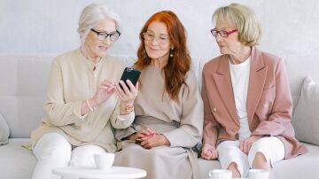 Mujeres charlando y consultando el m&oacute;vil 