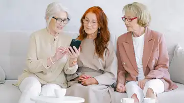 Mujeres charlando y consultando el móvil Mujeres charlando y consultando el móvil