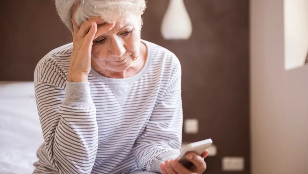 Mujer mayor mirando un teléfono móvil