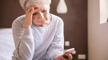 Mujer mayor mirando un teléfono móvil