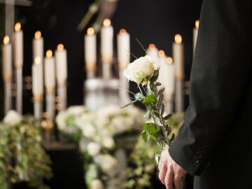Hombre con una rosa blanca en la mano durante un funeral