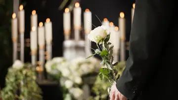 Hombre con una rosa blanca en la mano durante un funeral