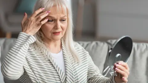 Mujer contemplando sus signos de envejecimiento Mujer contemplando sus signos de envejecimiento