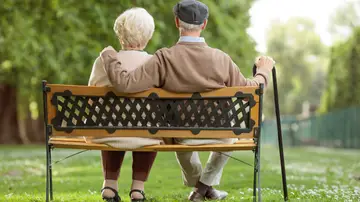 Una pareja mayor sentada en el banco de un parque