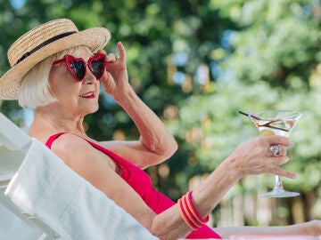Mujer mayor disfrutando de su tiempo libre en una tumbona con una bebida en la mano