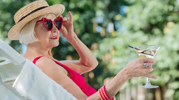 Mujer mayor disfrutando de su tiempo libre en una tumbona con una bebida en la mano