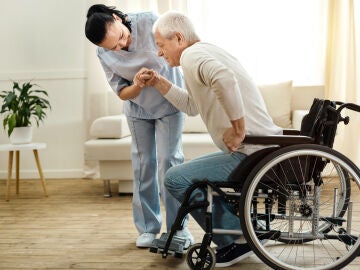 Hombre mayor en silla de ruedas tratando de levantarse con ayuda