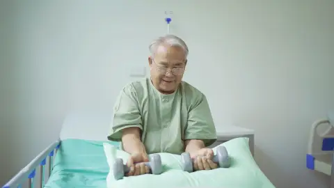 Hombre mayor hospitalizado haciendo ejercicio de fuerza Hombre mayor hospitalizado haciendo ejercicio de fuerza