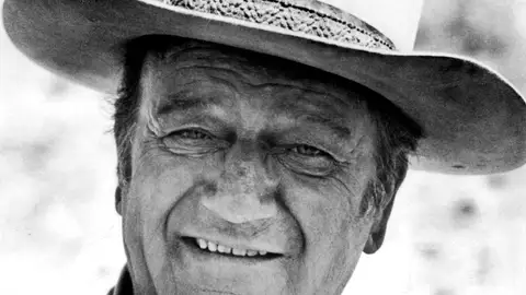 El actor estadounidense John Wayne con su característica indumentaria de cowboy El actor estadounidense John Wayne con su característica indumentaria de cowboy