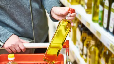 Un hombre cogiendo una botella de aceite de oliva Un hombre cogiendo una botella de aceite de oliva