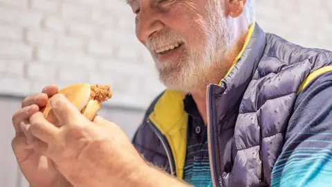 Hombre mayor comiendo una hamburguesa Hombre mayor comiendo una hamburguesa