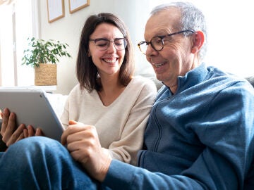 Una persona mayor utilizando una tablet junto a una mujer