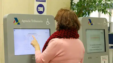 Una mujer recoge su turno en una oficina de la Agencia Tributaria Una mujer recoge su turno en una oficina de la Agencia Tributaria