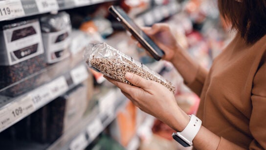 Mujer consultando un producto de supermercado en su m&oacute;vil