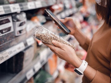 Mujer consultando un producto de supermercado en su m&oacute;vil