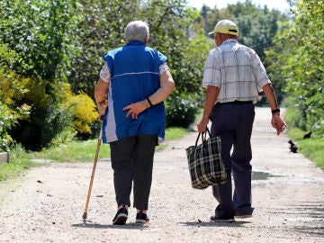 Pareja de personas mayores caminando por un pueblo