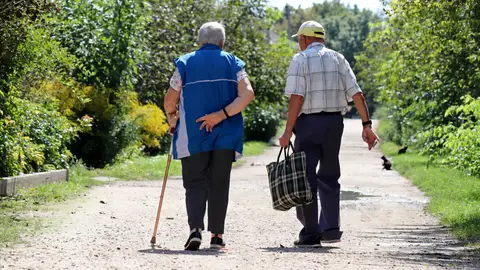 Pareja de personas mayores caminando por un pueblo Pareja de personas mayores caminando por un pueblo