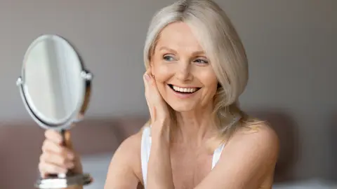 Mujer en sus 50 mirándose al espejo Mujer en sus 50 mirándose al espejo