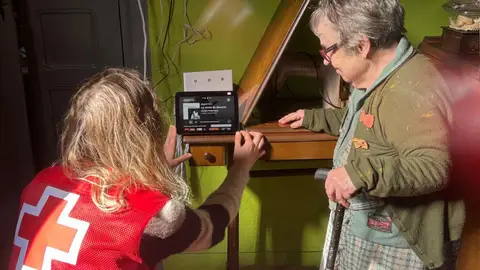Una voluntaria de Cruz Roja ayuda a una persona mayor participante en el programa Voces en red Una voluntaria de Cruz Roja ayuda a una persona mayor participante en el programa Voces en red