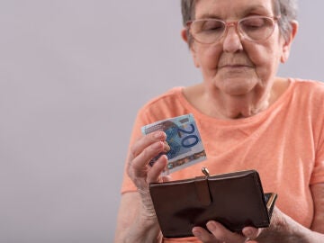 Mujer mayor guardando un billete de 20 euros en un monedero