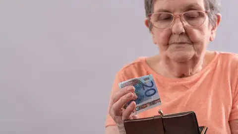 Mujer mayor guardando un billete de 20 euros en un monedero Mujer mayor guardando un billete de 20 euros en un monedero