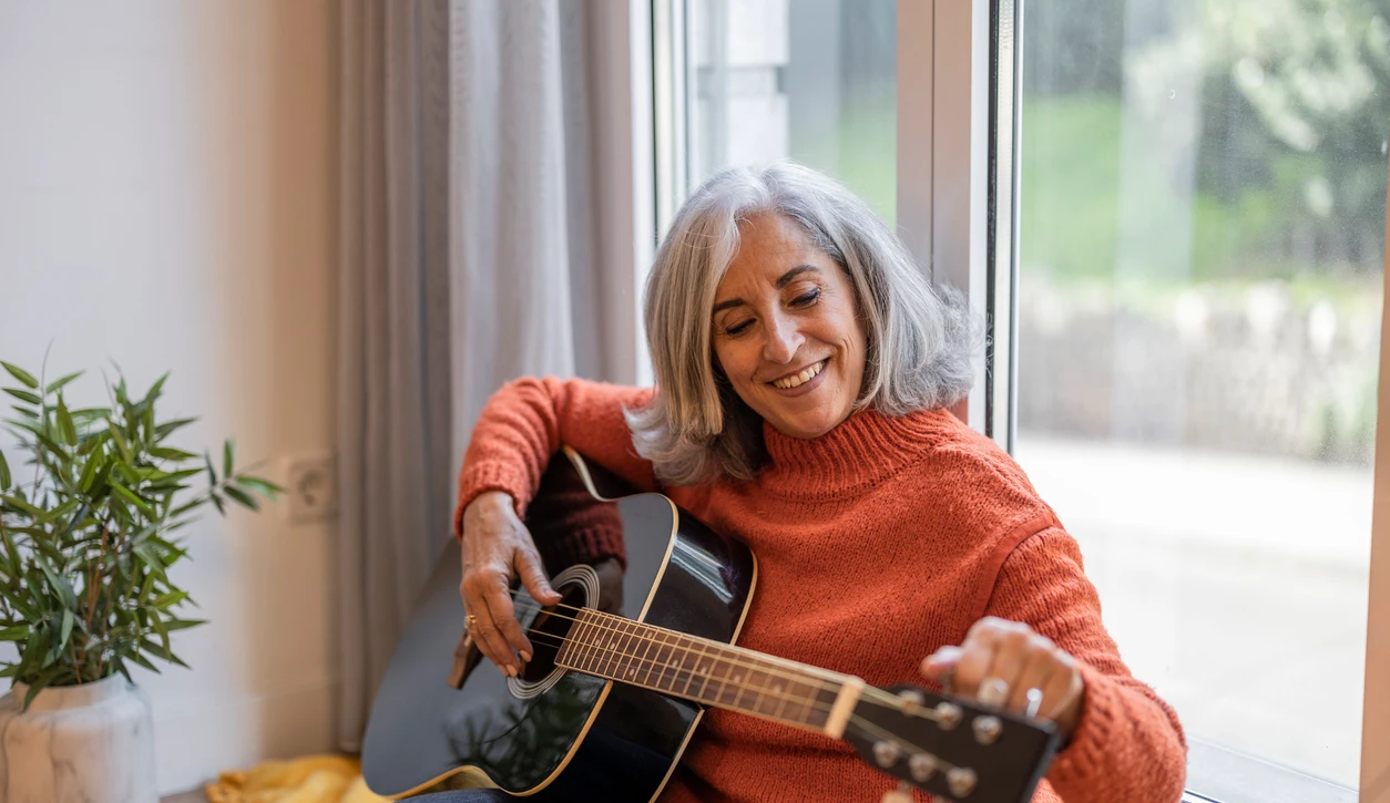 Una mujer afinando su guitarra