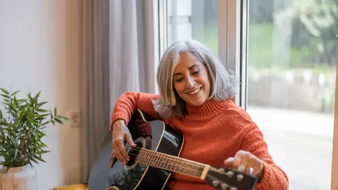 Una mujer afinando su guitarra Una mujer afinando su guitarra