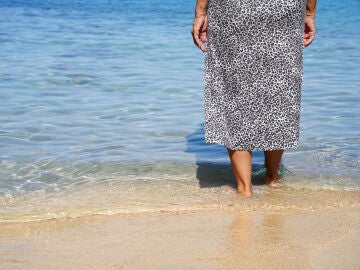 Mujer mayor caminando por la playa