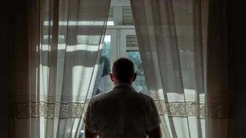 Hombre mayor mirando por la ventana Hombre mayor mirando por la ventana