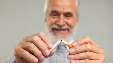 Hombre mayor rompiendo un cigarrillo Hombre mayor rompiendo un cigarrillo
