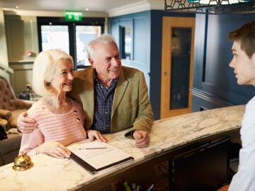 Pareja mayor registr&aacute;ndose en un hotel