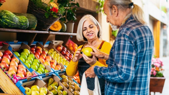 Mujer mayor atendiendo a un cliente en una fruter&iacute;a