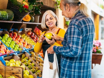 Mujer mayor atendiendo a un cliente en una fruter&iacute;a