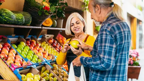 Mujer mayor atendiendo a un cliente en una frutería Mujer mayor atendiendo a un cliente en una frutería