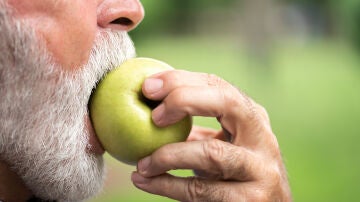 Hombre mayor comi&eacute;ndose una manzana