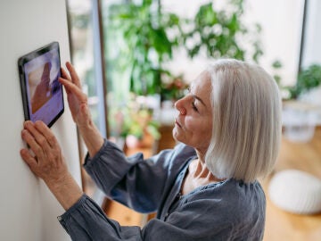 Mujer mayor con un dispositivo inteligente para controlar el hogar